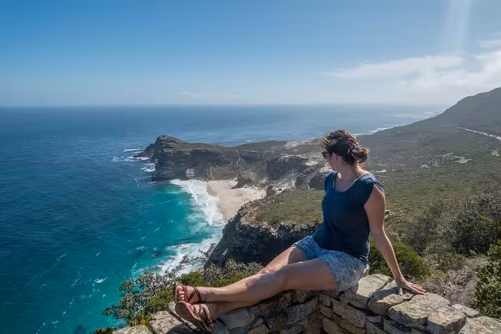 Visitor admires breathtaking views of Cape Point's rugged coastline and azure waters.