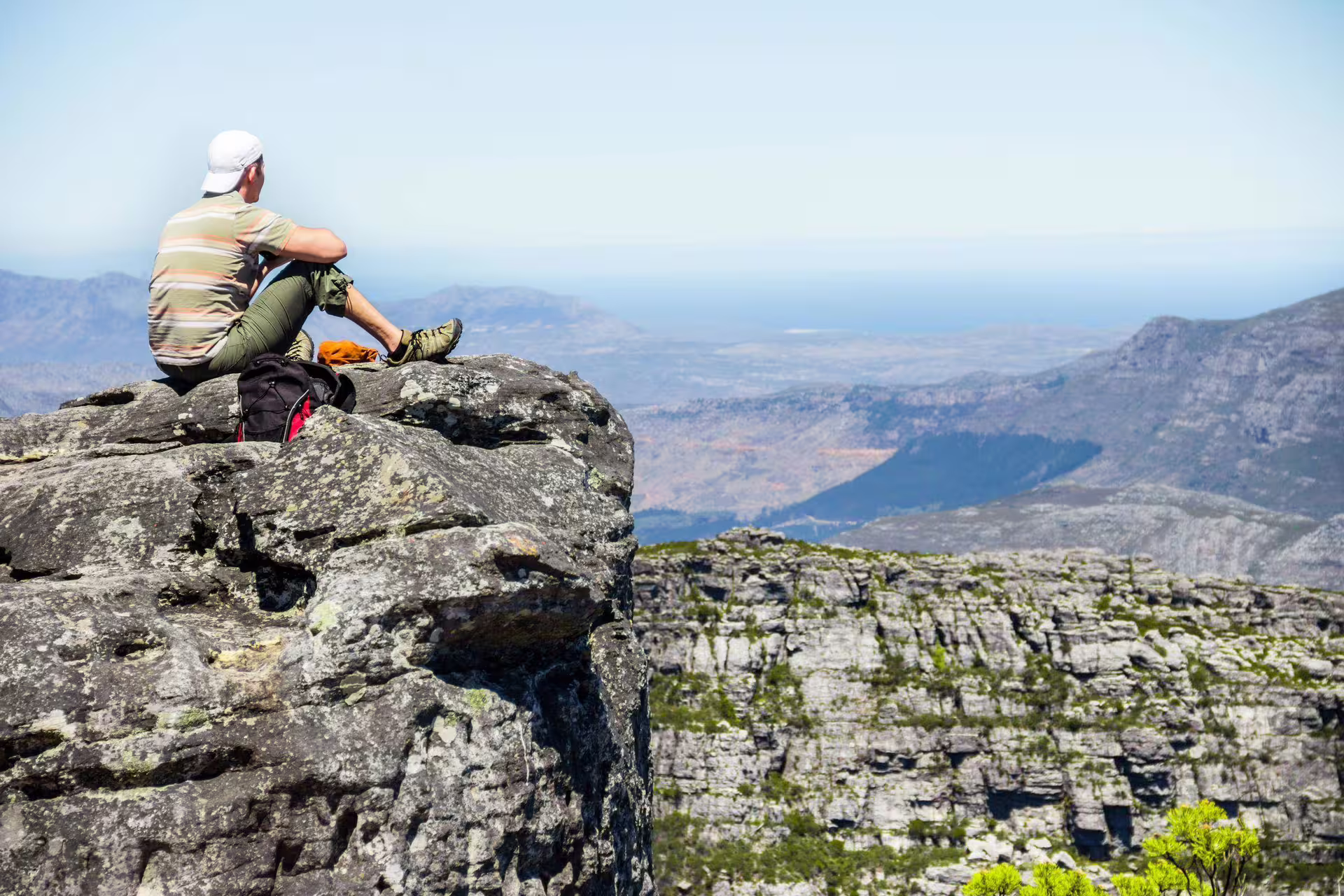 Hiker relaxing on a rocky cliff with panoramic views, part of the Cape Point tour experience.