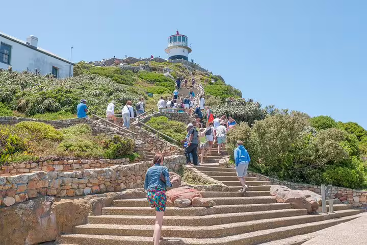 Tourists ascend the steps to the iconic Cape Point lighthouse, a must-see on the full-day tour from Cape Town.
