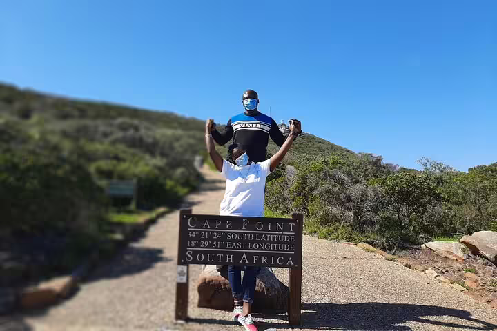 Visitors pose at Cape Point sign on a sunny day during Cape of Good Hope tour from Cape Town, South Africa.