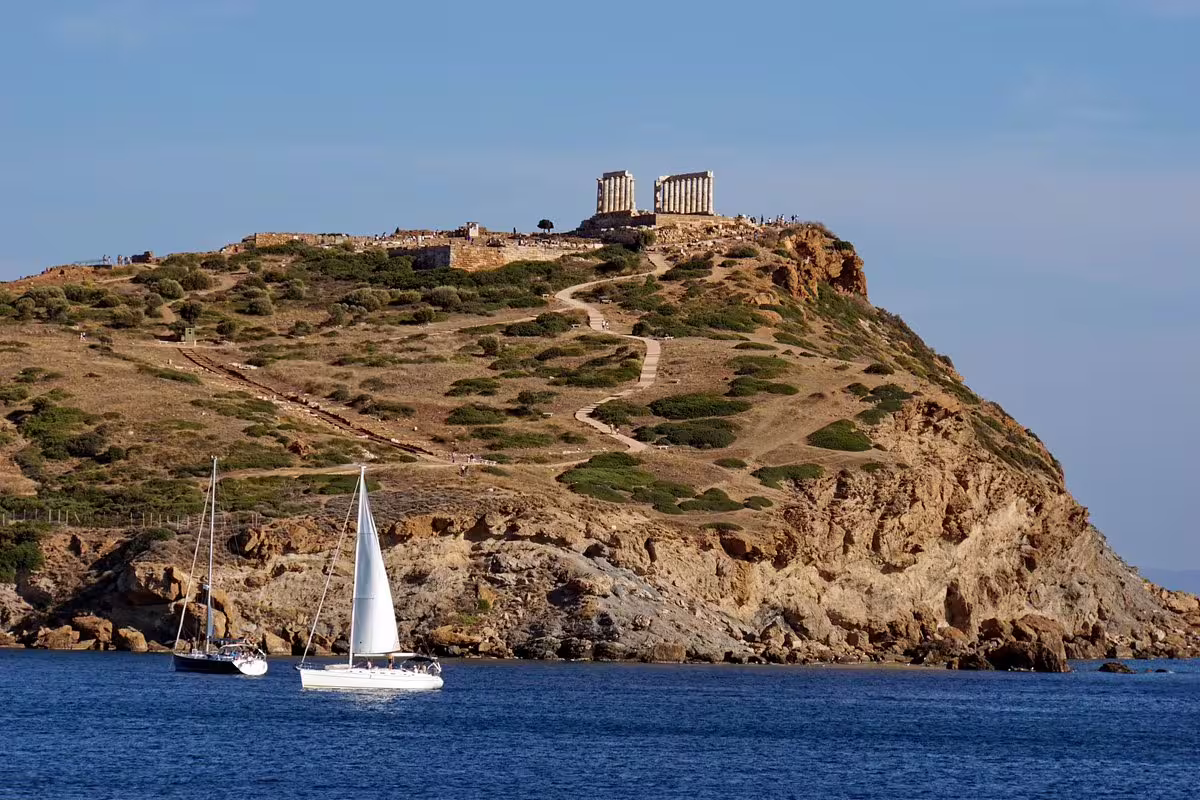 Cape Sounio cliff with Temple of Poseidon above the Aegean, sailboats below on Athens Riviera private tour