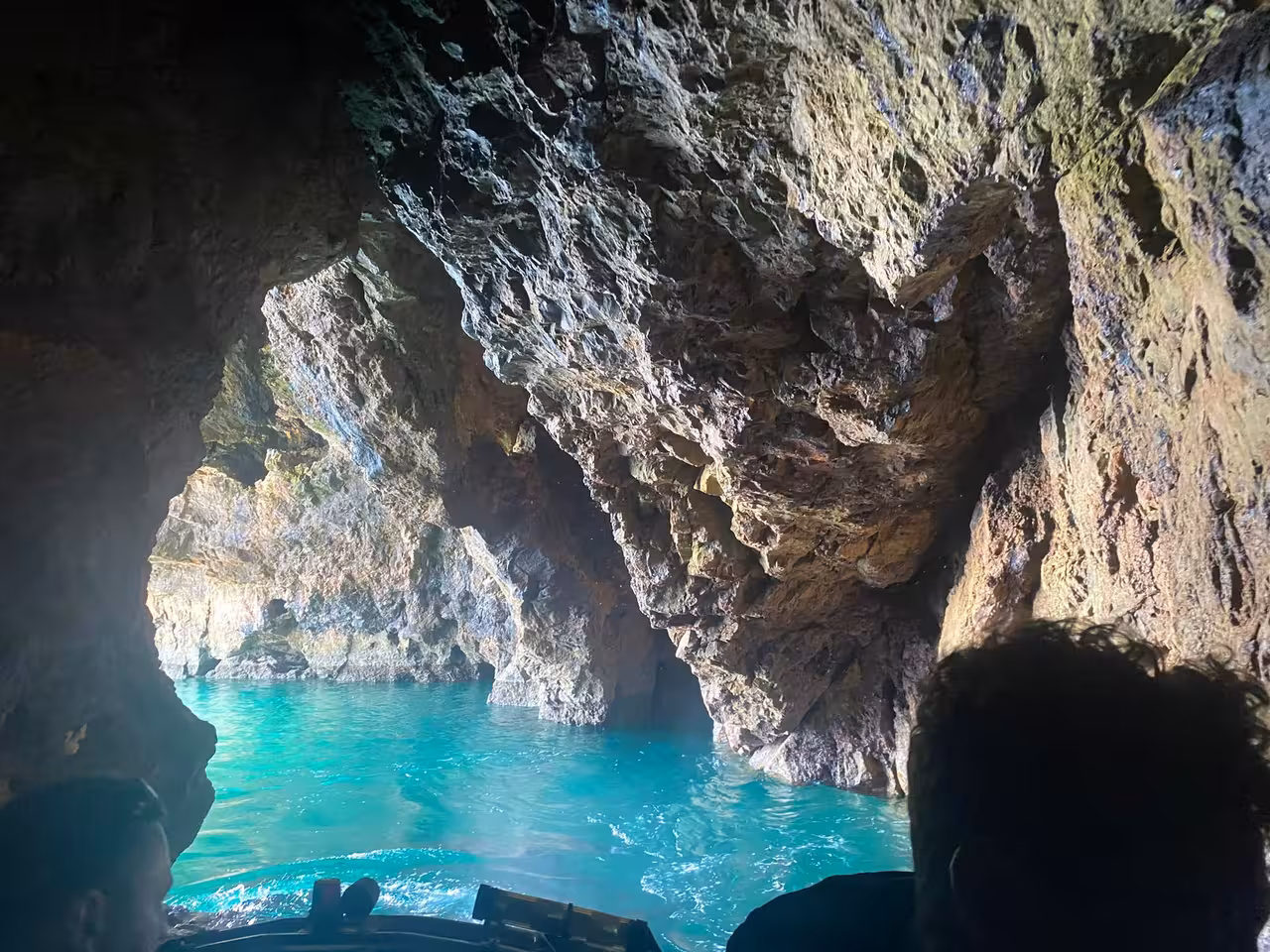 Inside Cape St. Vincent cave with stunning turquoise water and rugged rock formations, perfect for adventure tours.