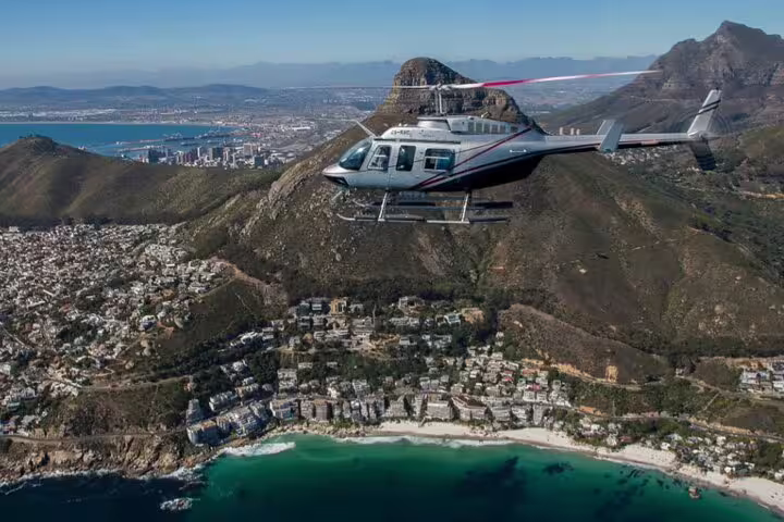 Helicopter soaring above Cape Town's coastline, showcasing breathtaking vistas on the Atlantico tour to Hout Bay.