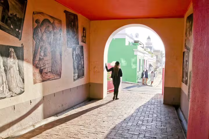 Colorful Bo-Kaap street with vibrant murals and tourists exploring, showcasing Cape Town's cultural heritage.