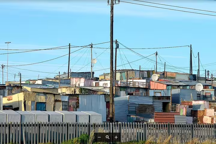 Metal rooftops and power lines in bustling Khayelitsha township, Cape Town, highlighting urban life and community.