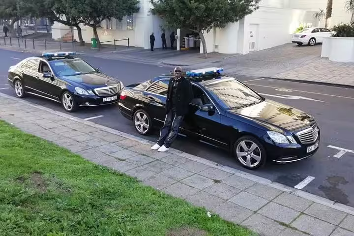 Luxury black sedan with driver ready for premium airport transfer service in Cape Town.