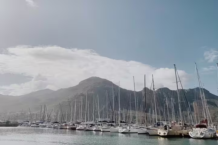 Picturesque marina in Cape Town with yachts docked against a backdrop of mountains, ideal for a scenic coastal journey.
