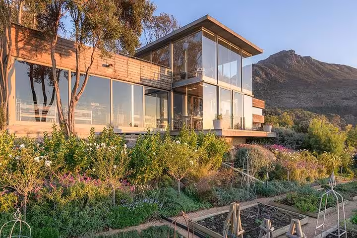 Modern glass-fronted house surrounded by lush gardens in Cape Town, perfect for a private city tour experience.