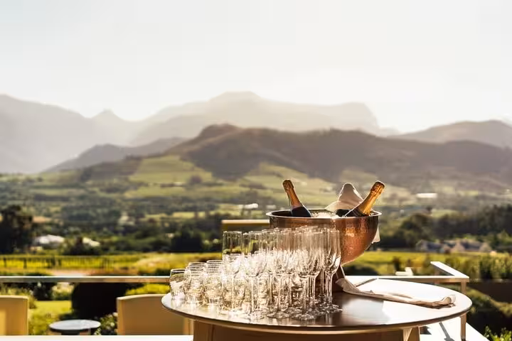 Scenic vineyard view with champagne and glasses on a table during a Cape Town wine tour.