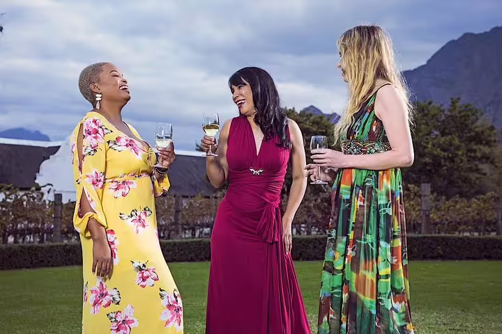 Three women enjoying wine amidst scenic vineyards at Kirstenbosch Gardens during a private tour outing.