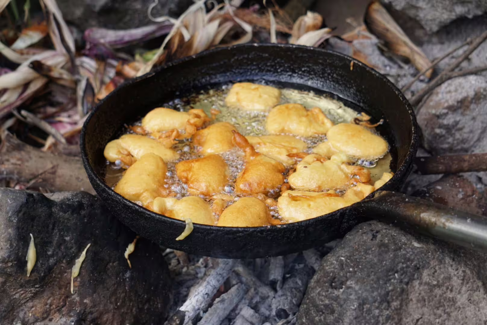 Local Cape Verdean fritters frying in a rustic pan during a traditional lunch experience on Serra Malagueta hike.