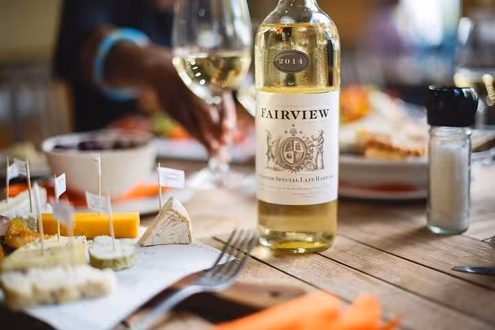 A selection of artisan cheeses paired with Fairview white wine, highlighting the gourmet experience of Cape Winelands tours.