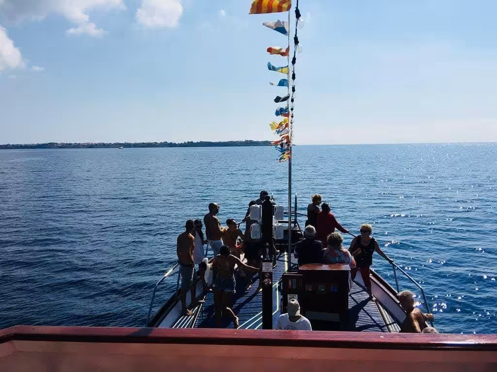 Visitors on a boat deck admire the vast sea view during a Capo Rizzuto marine protected area tour.