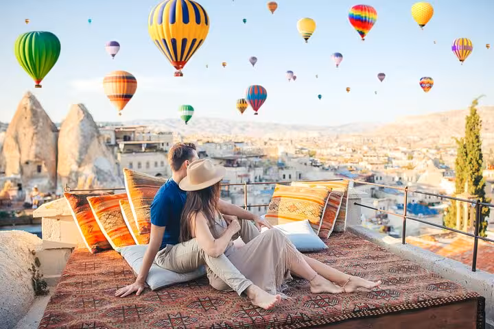 Couple on Göreme rooftop watching Cappadocia hot air balloons, part of 2-day 1-night Istanbul flight tour