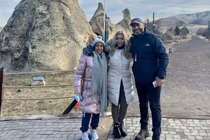 Small group photo stop by Cappadocia fairy chimney rock formations during full-day guided tour with lunch