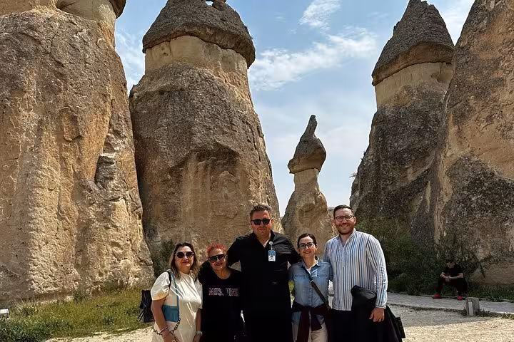 Small group posing at Cappadocia fairy chimneys during full-day guided tour with lunch in Göreme
