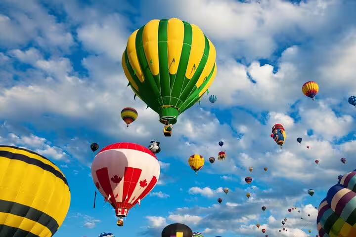 Vibrant hot air balloons, including a green and yellow design, float against a bright blue sky in an exciting aerial spectacle.