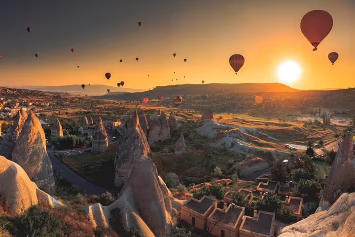 Hot air balloons float above Cappadocia's unique rock formations at sunrise, promising an unforgettable champagne adventure.