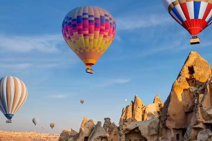 Vibrant hot air balloons float over Cappadocia's unique rock formations, creating a stunning aerial view at sunrise.