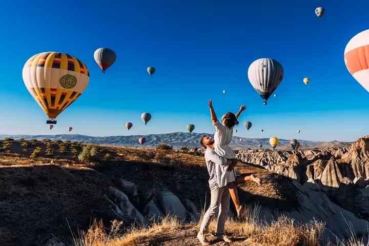 Couple watches Cappadocia hot air balloons over valleys, a highlight of the Cappadocia North Tour experience