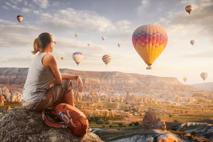 Traveler watching Cappadocia hot air balloons at sunrise on 2-day highlights tour from Istanbul