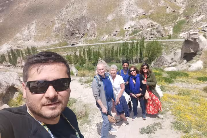 Guests with guide on Cappadocia private tour from Istanbul by plane, scenic valley walk near cave dwellings
