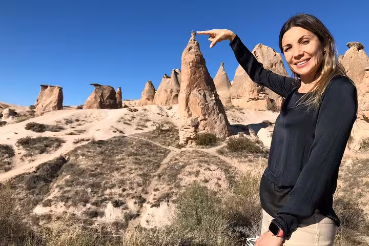 Traveler posing by Cappadocia rock formations on private tour with English speaking guide and luxury van