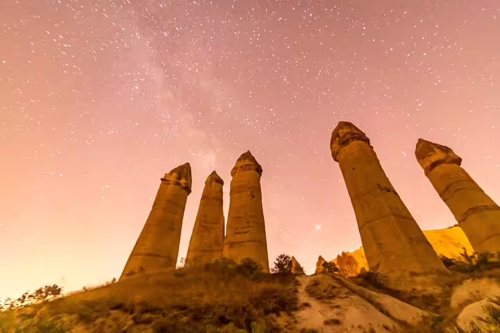 Majestic rock formations in Cappadocia under a starry sky, highlighting the allure of a private tour from ASR-NAV airport.