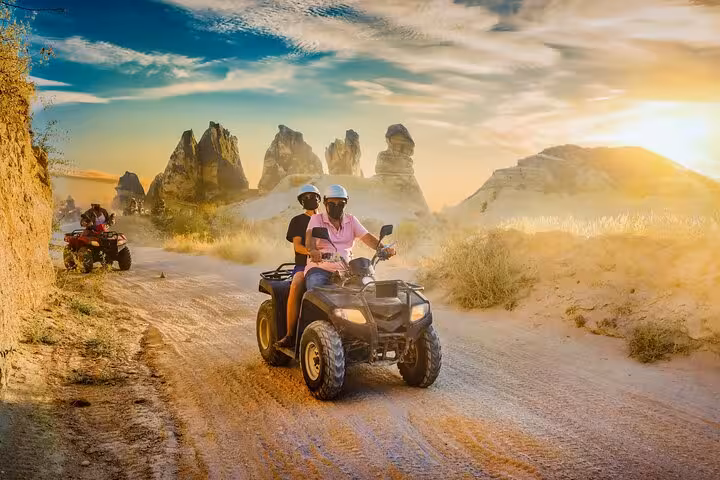 Riders on Cappadocia sunset ATV tour driving through valleys with fairy chimneys in golden hour light