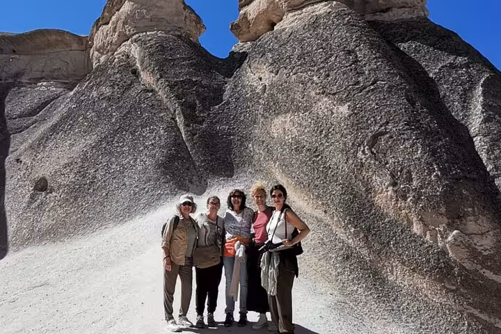 Grupo de viajeros posa junto a chimeneas de hadas en Cappadocia, tour en español de 2 días con vuelos