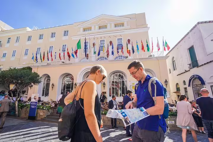 Visitors exploring the vibrant streets of Capri with colorful flags and historic architecture on a guided tour.