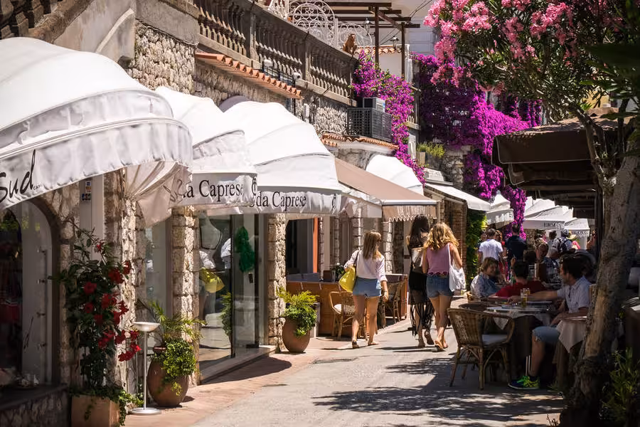 Charming Capri street lined with boutiques and vibrant flowers, perfect for leisurely strolls on the Capri & Anacapri tour.