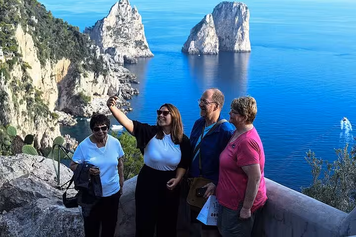 Visitors capturing memories with Faraglioni rocks backdrop on Capri & Anacapri full-day hydrofoil tour.