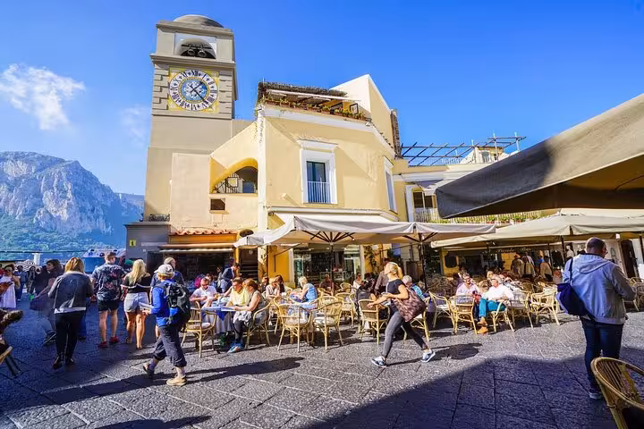 Visitors relax at a bustling cafe in Capri's vibrant Piazzetta, a highlight of the Capri & Anacapri Select tour.