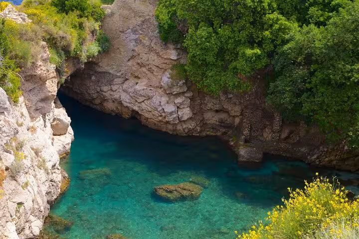 Crystal clear waters and lush greenery at a secluded grotto on the Capri boat tour with Blue Grotto exploration.