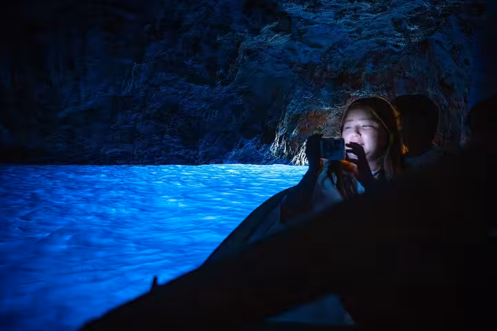 A visitor captures the mesmerizing blue glow inside Capri's Blue Grotto during a guided tour.