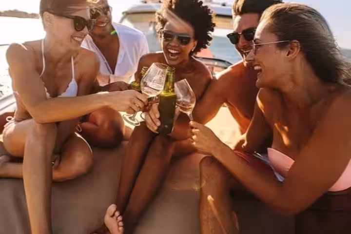 Group of friends celebrating with drinks on a boat during a sunny day trip around Capri's stunning coastline.