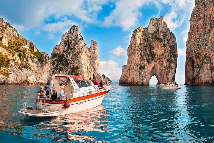 Tourists enjoying a boat excursion near Capri's iconic cliffs, highlighting the beauty of Amalfi's coastal adventures.