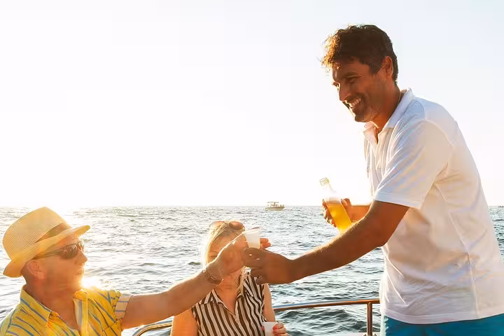 Guests enjoying drinks served by a crew member during sunset on a Capri boat excursion from Sorrento.