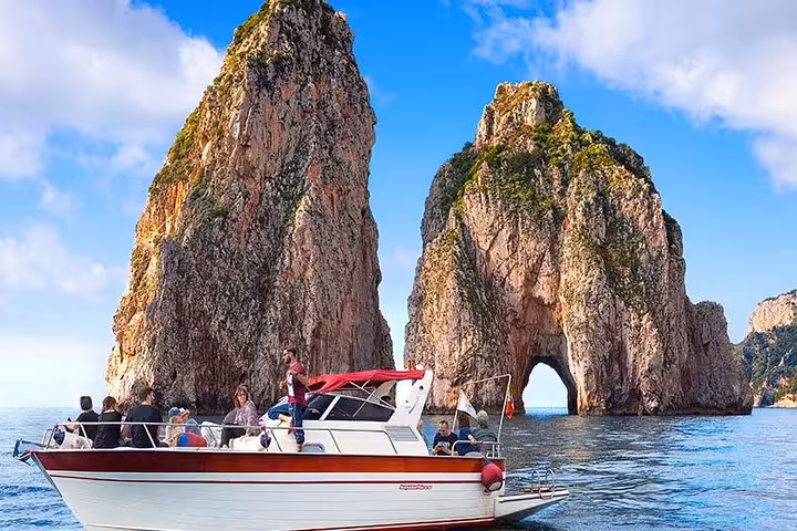A boat tour near the iconic Faraglioni rocks during a Capri excursion starting from Positano.