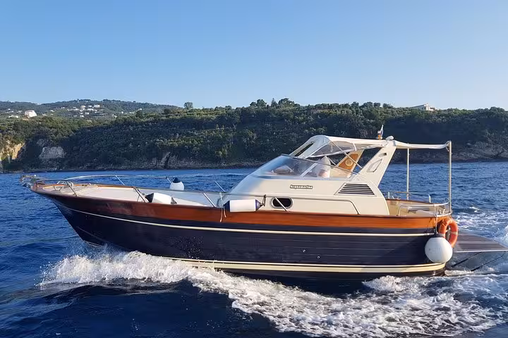 Elegant boat cruising through blue waters near Positano on a small group Capri excursion.