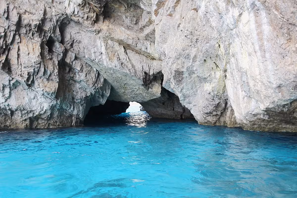 Stunning view of a rocky sea cave entrance with vibrant turquoise waters on a Capri boat tour.