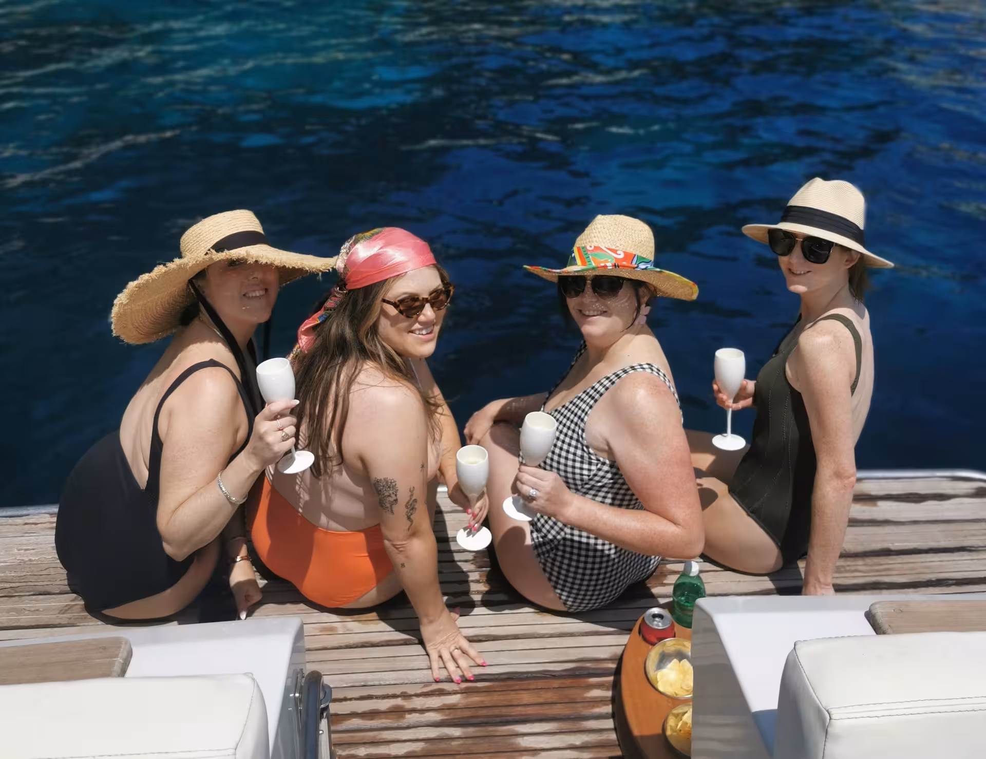 Group of women enjoying limoncello on a Capri boat tour from Sorrento, relaxing on deck under the sun.