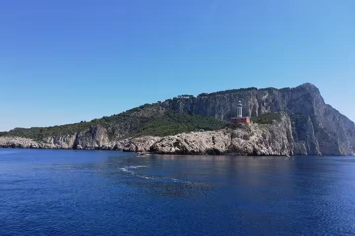 Breathtaking view of Capri's coastline with a lighthouse, a highlight of the Typical Gozzo boat tour.
