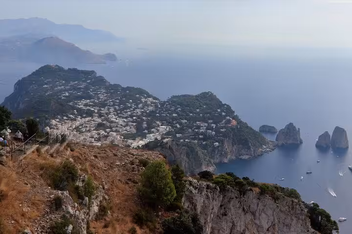 Breathtaking aerial view of Capri's coastline featuring the iconic Faraglioni rock formations and blue waters.