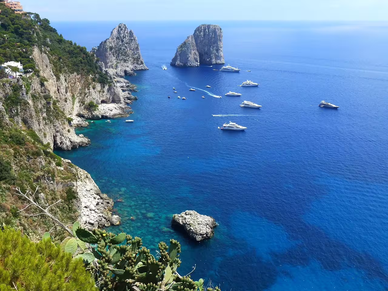 Turquoise bay of Capri with Faraglioni rocks and yachts cruising clear Tyrrhenian waters on Li Galli and Capri boat trip