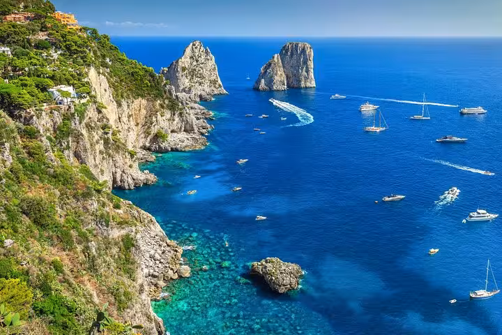 Breathtaking view of Capri's iconic Faraglioni rock formations and turquoise sea on a serene private boat tour.