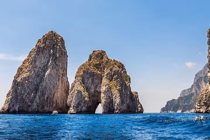 Iconic Faraglioni rock formations rise majestically from the azure waters of Capri, a highlight of the private tour.