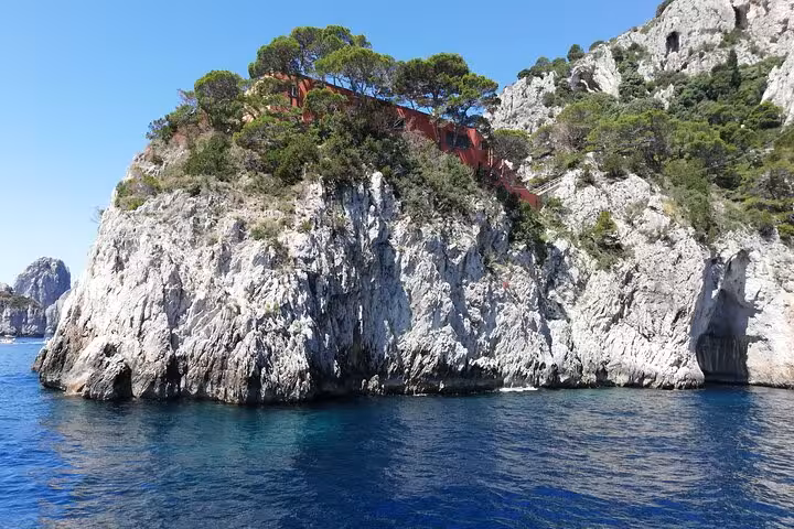 Breathtaking view of rocky cliffs topped with greenery on the Faraglioni cruise around Capri island.