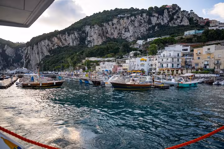 Scenic view of Capri's vibrant harbor with boats anchored against a backdrop of towering cliffs.